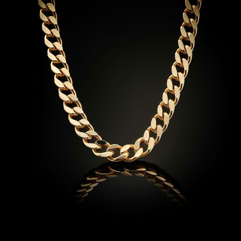 A heavy gold curb chain against a black background